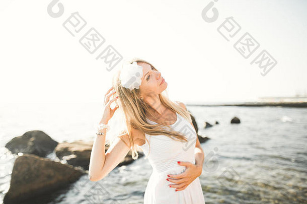 穿着白色连衣裙的<strong>浪漫</strong>美丽新娘在海石上摆姿势