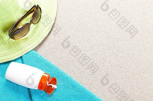 假期背景。太阳镜防晒霜帽子和毛巾在沙滩上。带拷贝空间的夏季概念