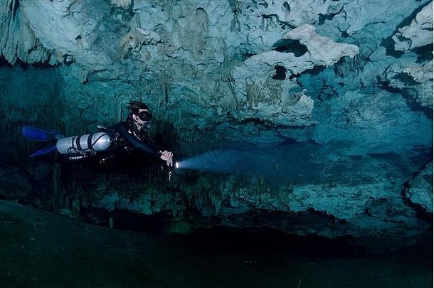 侧装技术潜水员在墨西哥梦幻之门纪念碑独特的石灰岩地层周围游泳。