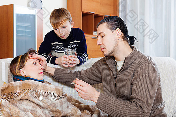 男子和儿子照顾患高烧的不适妇女