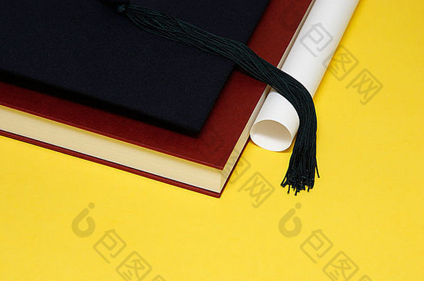 毕业帽放在一本厚厚的书和一卷纸上