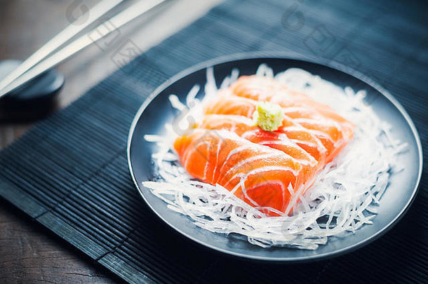 木桌上放着新鲜生鲑鱼刺身和日式<strong>萝卜丝</strong>。