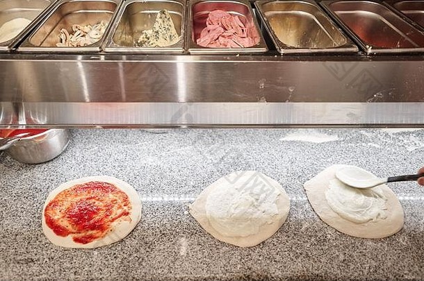 将烹饪比萨饼的半成品填充在冷桌中，作为空白。意大利餐厅的传统木制烤箱。原汁原味的那不勒斯披萨。红色