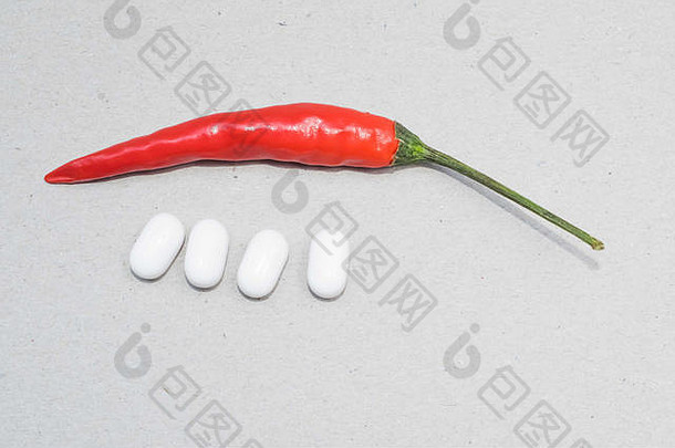 单瓣红辣椒和四颗白色胶囊，背景为白色
