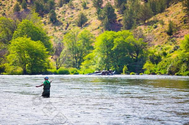 在俄勒冈州的Deschutes河上钓鱼的经验丰富的飞钓渔民，站在水中寻找鱼。