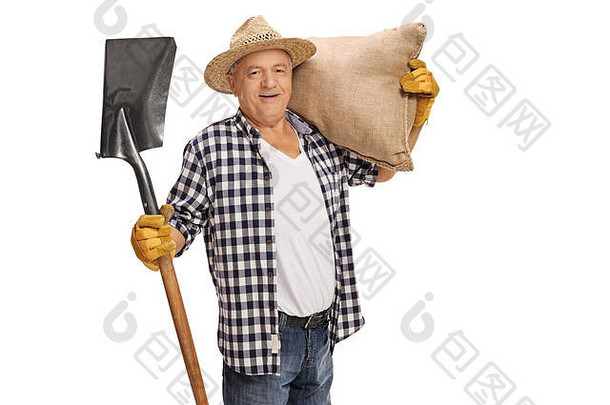 快乐的老农夫拿着一把铲子和一个麻袋在白色背景上摆姿势