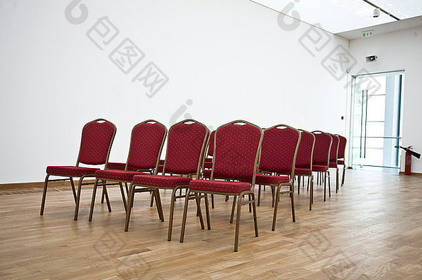 在空荡荡的<strong>会议</strong>大厅里摆放着红色的椅子，上面铺着层压板。