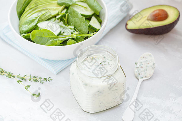 酸奶芥末酱配绿色菠菜鳄梨沙拉，浅色背景。素食健康食品的概念。