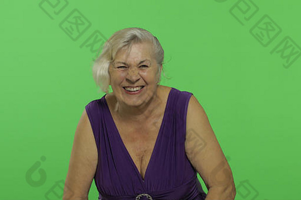 一位老妇人在笑。穿着紫色连衣裙的快乐的老奶奶。放置您的徽标或文字。色度键。绿色屏幕背景
