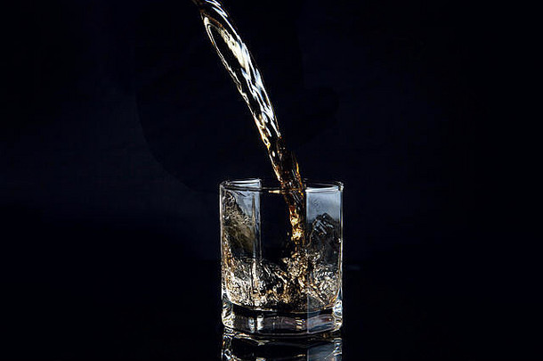 威士忌倒玻璃冰孤立的反光黑色的表面威士忌飞溅玻璃滴饮料玻璃