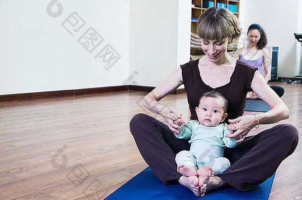 妈妈。婴儿坐着盘腿瑜伽瑜伽类