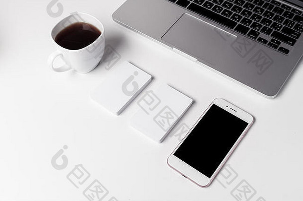 在笔记本电脑旁放上咖啡、名片和智能手机