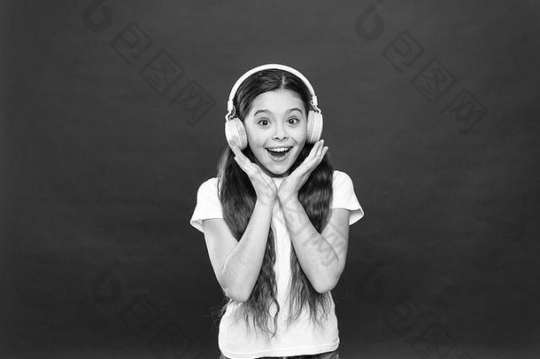 女孩戴着红色背景的耳机听音乐。播放列表概念。音乐品味。音乐在青少年的生活中起着重要的作用。音乐对青少年的情感、感知世界有着强大的影响。