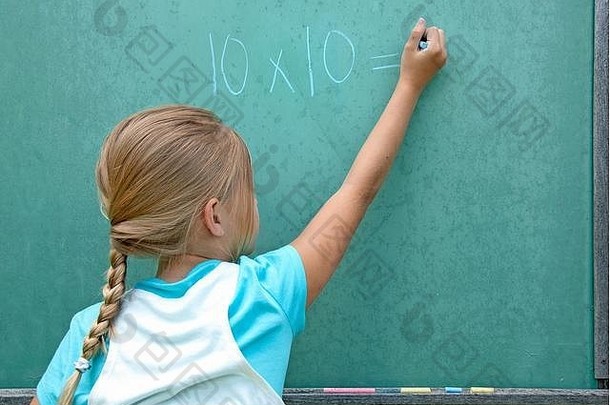 年轻的白人女孩在绿色黑板上写<strong>数学题</strong>