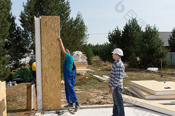 一组建筑工人在住宅区新建房屋的新铺设地板上绝缘木墙板