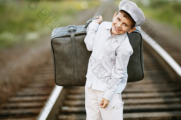 铁路上提着手提箱的男孩