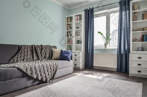 白色书柜、灰色沙发和蓝色墙壁的轻巧舒适的青少年房间