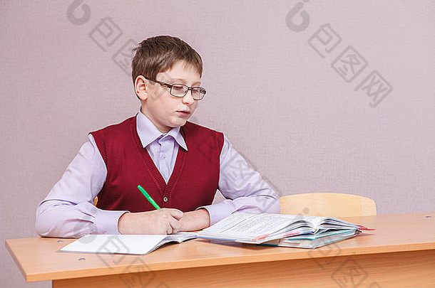 戴眼镜的男孩坐在书桌旁写字