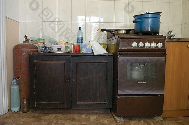 乌克兰敖德萨。旧的基本厨房，棕色独立烤箱，旧的蓝色搪瓷壶和不匹配的橱柜。