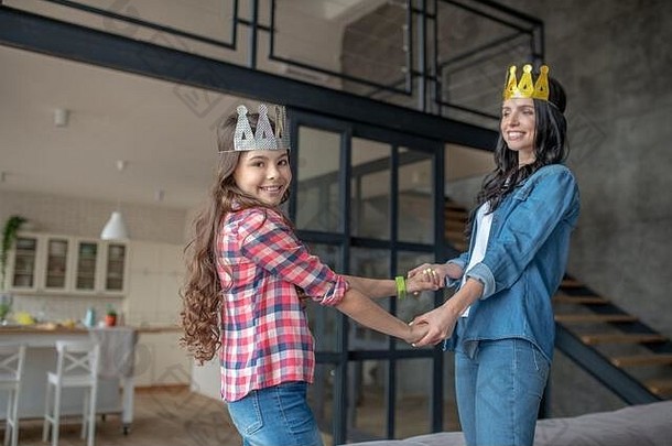 妈妈和女儿戴着皇冠，手牵着手