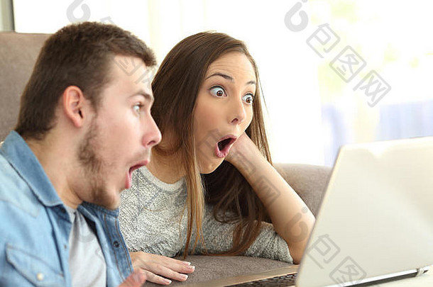 一对惊讶的夫妇张着嘴上网，笔记本电脑躺在客厅的沙发上