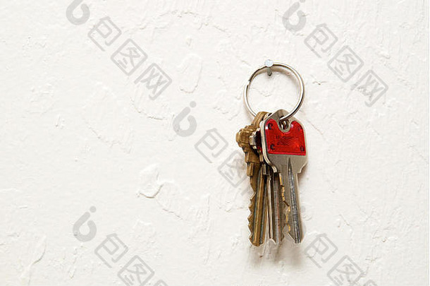 有三把钥匙的钥匙环挂在有纹理的灰泥内墙上的钉子上。使用拷贝空间。