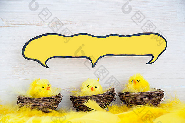 坐着复活节小鸡复活节篮子巢黄色的羽毛白色木背景羽毛漫画