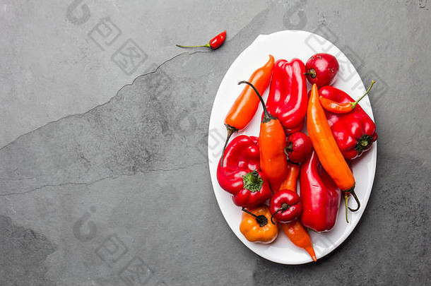 白色盘子上的辣椒和甜椒，石板背景，俯视图。