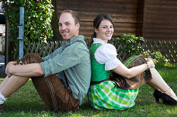 穿着传统巴伐利亚服装的夫妇坐在草地上