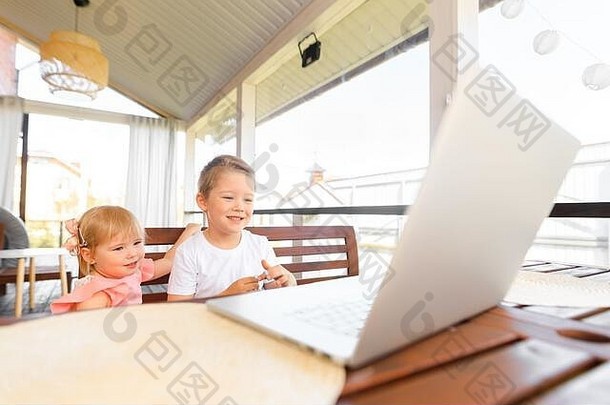 小朋友们微笑着，兄弟姐妹一起玩笔记本电脑，交流视频会议聊天。