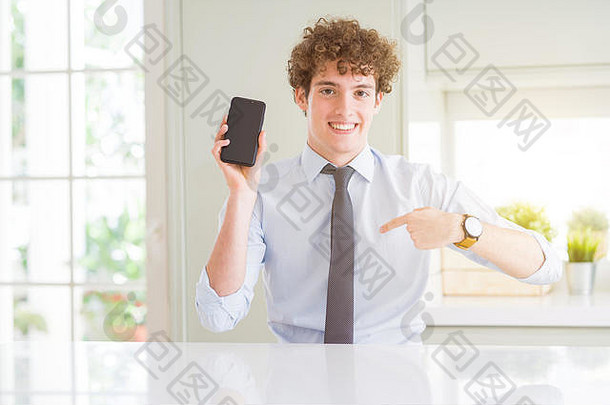 年轻的业务男人。显示智能手机屏幕办公室惊喜脸指出手指