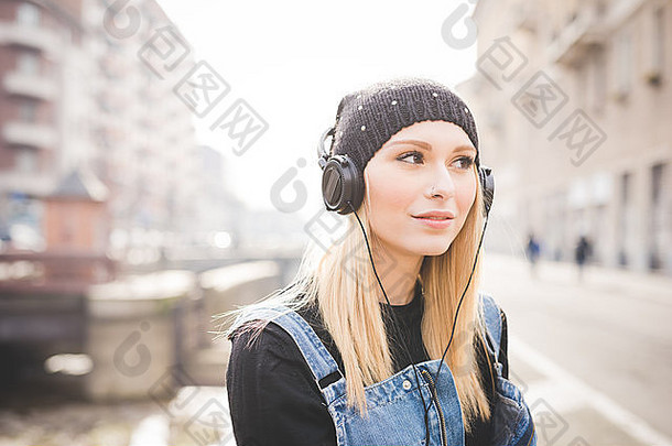 肖像年轻的美丽的金发女郎直头发女人城市耳机听音乐俯瞰左微笑幸福放松概念