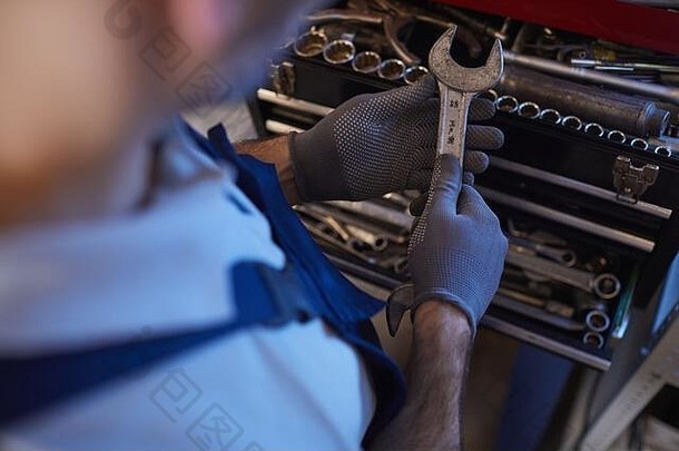 汽车修理工在车库车间选择工具时的高角度特写，空间