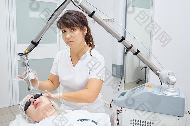 医疗沙龙女员工使用有效的钕激光去除年轻患者脸上多余的疤痕