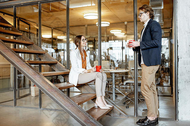 年轻的多少男人。女人谈话坐着楼梯咖啡打破现代办公室