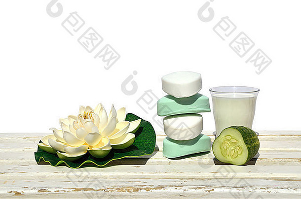 白色木质表面涂有黄瓜、牛奶和人工莲花的乳白色肥皂