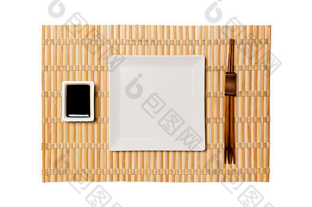黄色竹垫背景上的白色方形空盘子，上面放着寿司和酱油用的筷子。带有供您设计的空间的俯视图。
