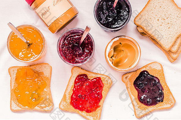 烤面包三明治配花生酱和果酱覆盆子、蓝莓、橙色顶视图