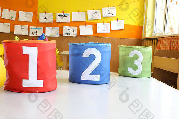 幼儿园教室的桌子上有红、绿、蓝两种颜色的罐子，上面写着一、二、三