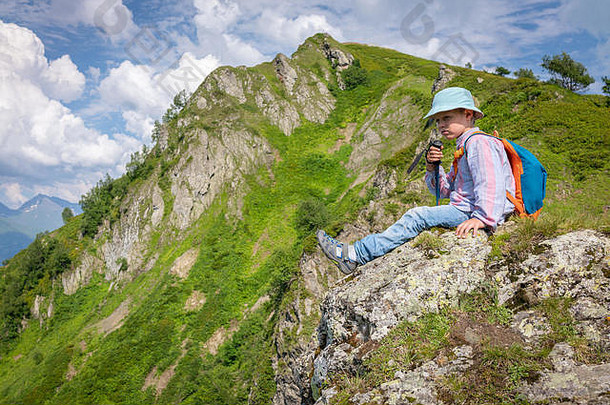 一个在巴拿马旅行的男孩拿着<strong>登山杖</strong>和背包在山顶上休息。高加索，俄罗斯