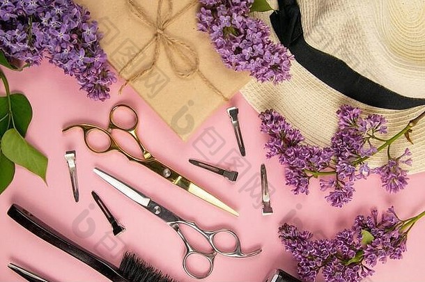 理发工具-剪刀，梳子和淡紫色的花，粉红色背景的礼物。美的概念。平面布置，俯视图
