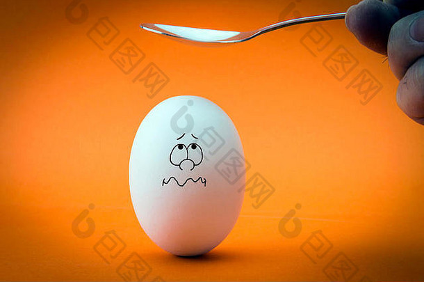 在橙色背景上敲碎蛋头。害怕的鸡蛋看着勺子。