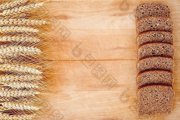 乡村面包和小麦放在一张老式<strong>木板</strong>桌子上。旧木背景，有自由文本空间。
