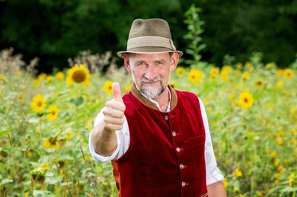 肖像英俊的巴伐利亚男人。站花园拇指