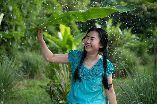 肖像年轻的亚洲女人黑色的头发持有香蕉叶下雨绿色花园背景