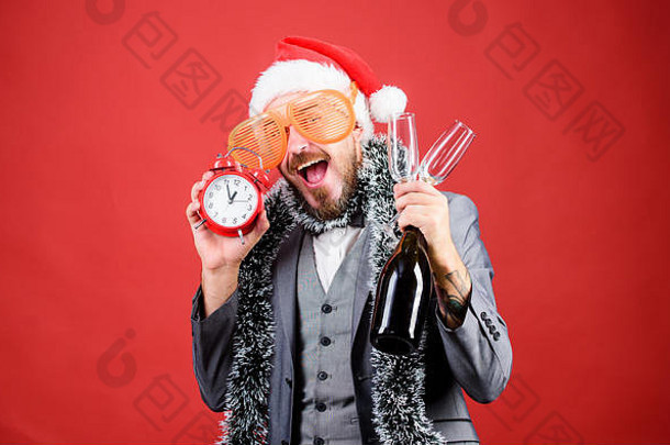 干杯的概念。参加办公室聚会。冬季派对的想法。快午夜了。是庆祝新年的时候了。圣诞<strong>晚会</strong>。男人胡子时髦的圣诞老人帽香槟酒瓶。闹钟公司<strong>党</strong>。