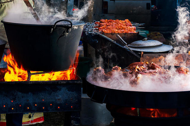 乌克兰赫查—2018年1月27日：猪肉屠夫<strong>大赛</strong>。煮沸的大锅着火了。在热气腾腾的盘子上煮肉。远处的空白烧烤