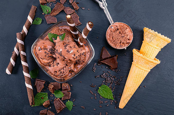 在玻璃碗里舀巧克力冰淇淋，在黑色板岩板上放上<strong>威化</strong>饼干棒、蛋<strong>卷</strong>和巧克力。用勺子把注意力集中在碗上巧克力冰淇淋