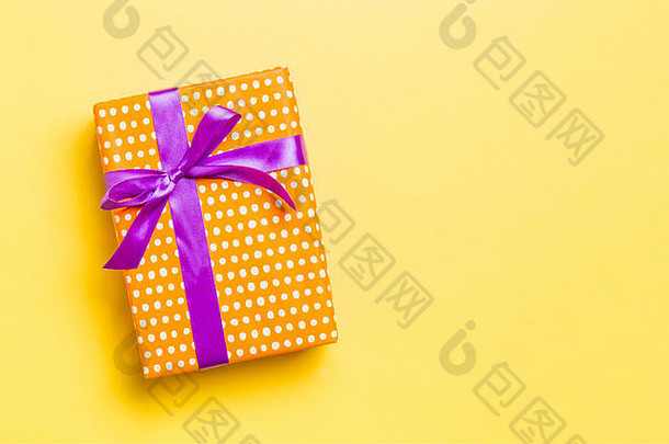 圣诞或新年礼物盒，带紫结，背景为黄色，顶视图带有复印空间。