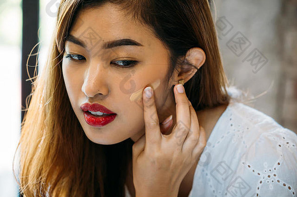 特写镜头年轻的亚洲女人红色的嘴唇应用校正器脸模糊背景